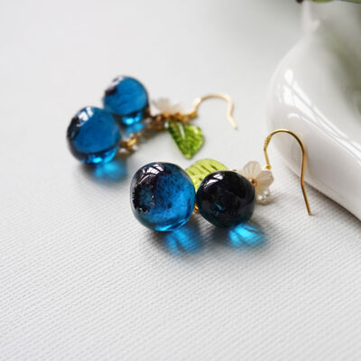 Handmade resin blueberry earrings featuring white flower detail and gold tone ear wires