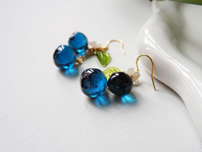 Handmade resin blueberry earrings featuring white flower detail and gold tone ear wires